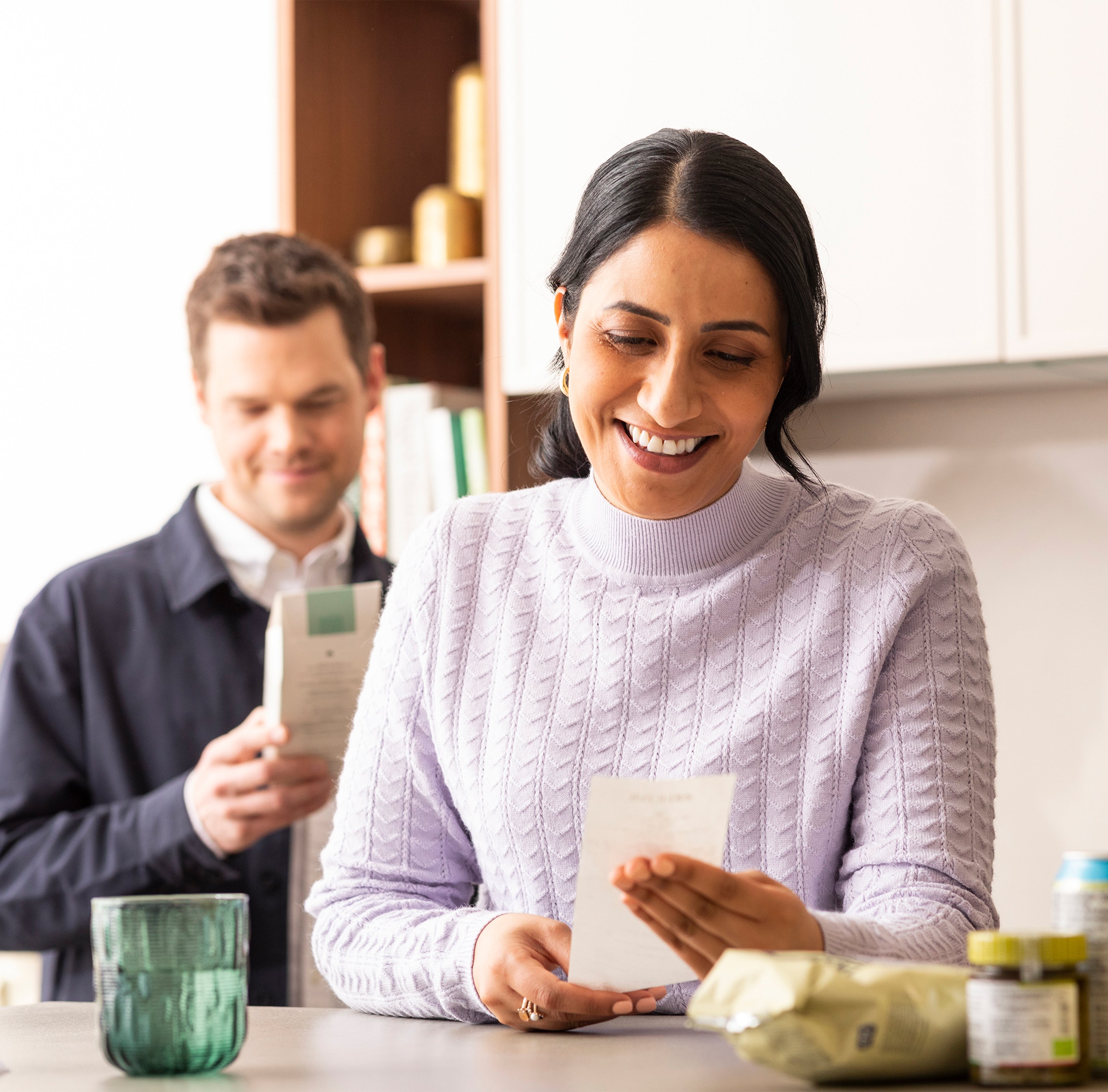 A woman and a man are reading in a kitchen 