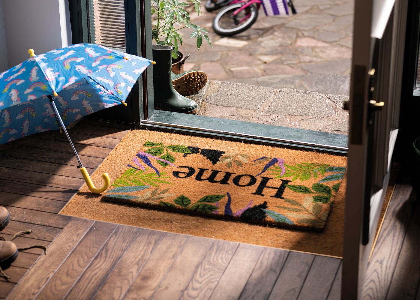 An umbrella is open indoors on a mat next to the front door of a house.