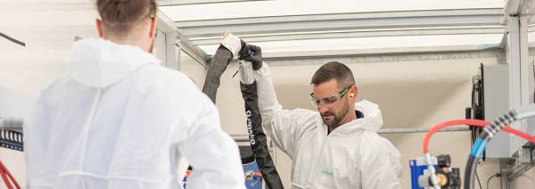 2 men working in PPE working with insulation equipment